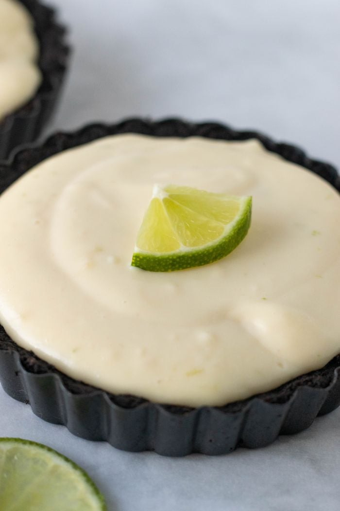 a close up of a no bake lime tart with a wedge of lime on top for garnish